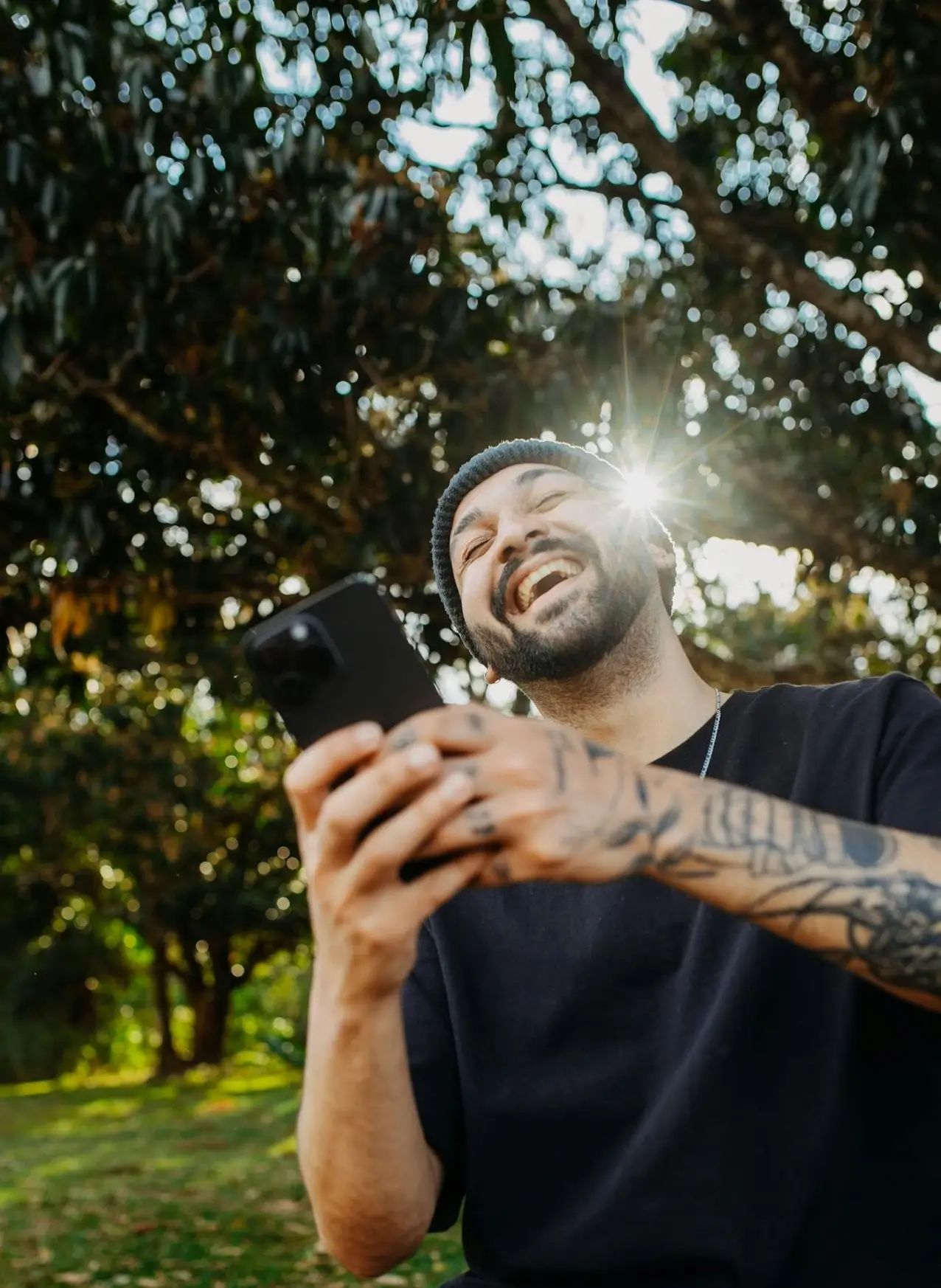 Happy man with mobile sunny tree background.